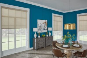 A dining room with blue walls and white windows with beige shades.